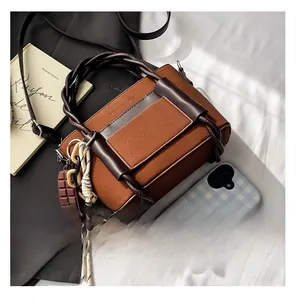 Detail of a brown textured leather bag with unique woven handle and fashion branding