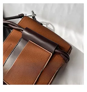 Detail of brown litchi grain leather bag featuring woven rope strap and silver hardware