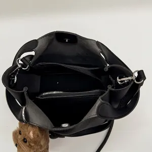 Black pebbled leather bucket bag with inner zipper compartment and teddy bear charm