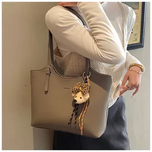 Close-up of elephant gray lychee leather tote bag with a cute leopard bow bear charm
