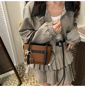 Detail of tan leather crossbody bag with braided handle and chocolate charm