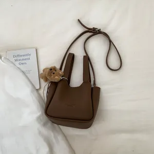 Detailed top view of dark brown bucket bag with lychee texture and plush bear charm