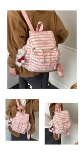 Detail eines rosa gestreiften Plüschrucksacks mit weichem Fleece und Bärenanhänger