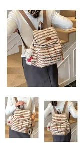 Detail eines gestreiften Plüschrucksacks mit Kordelzug und kleinem Bären-Anhänger