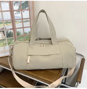 Detail of a beige waterproof nylon travel bag with adjustable strap on a wooden table