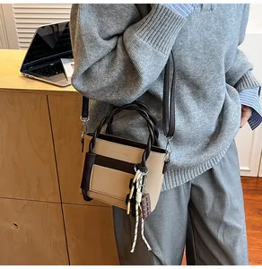 Detail of a beige and brown crossbody bag with woven handle and chocolate pendant