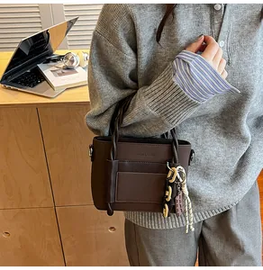 Detail of dark brown leather handbag with debossed fashion text and woven rope charm