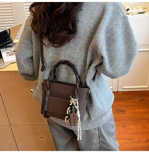 Detail of dark brown lychee leather tote with braided handles and decorative charms