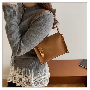 Détail d'un sac sous le bras marron vintage avec rivets dorés et fermoir tournant en métal