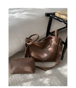 Detail of a brown lychee pattern leather tote bag with matching zipper pouch and strap