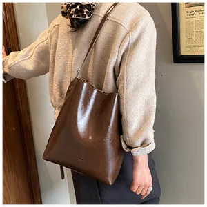 Detail of dark brown wax leather bucket bag showing polished texture and shoulder strap