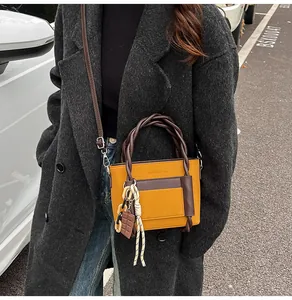 Detail of yellow and brown crossbody bag with woven handles shown in outdoor street style