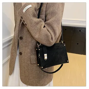 Détail d'un sac bandoulière noir mat avec fermoir doré rotatif et rivets élégants