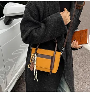 Detail of yellow and brown crossbody bag with woven handle and lychee texture