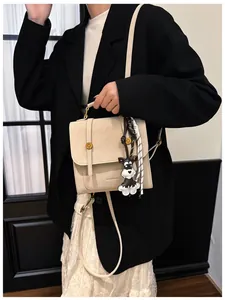 Dettaglio di un piccolo zaino beige con ciondolo a forma di schnauzer e nastro intrecciato