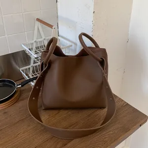 Brown lychee leather bucket bag with rivet wide strap and ring handle in retro style