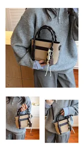 Detail of two-tone tote bag featuring woven rope handles and chic chocolate charm