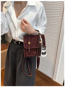 Dettaglio della borsa a tracolla vintage bordeaux con cuciture bianche e charm a cane
