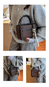 Close-up of deep brown leather tote bag with braided rope handles and chain charms
