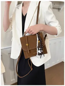 Dettaglio zaino vintage marrone con cuciture bianche, logo dorato e ciondolo a cane