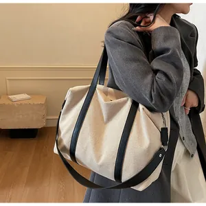 Close-up of beige canvas tote bag with black leather straps and woven texture detail