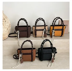 Collection of five elegant faux leather handbags with woven handles on display