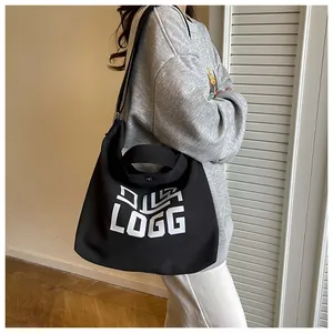 Detail view of the black canvas tote bag featuring white LOGG print and wide strap