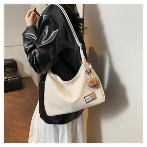 Close-up of cream PU leather tote bag featuring a cute bear pendant and fashion patch