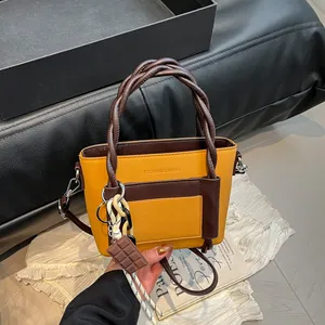 Yellow textured leather crossbody bag with woven handles and chocolate charm detail