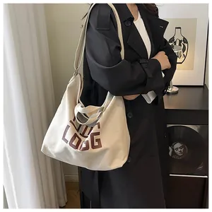 Detail of minimalist cream canvas tote bag with brown logo and adjustable shoulder strap