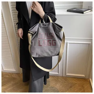 Detail of grey canvas tote bag with red LOGG print and beige shoulder strap worn by model