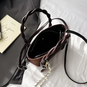 Minimalist brown and black contrast leather handbag with twisted handles and woven rope detail