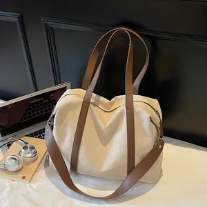 Large beige canvas tote bag with brown leather straps for commuting and travel