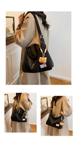 Detail view of large black tote bag featuring a cute brown plush bear charm and matte texture