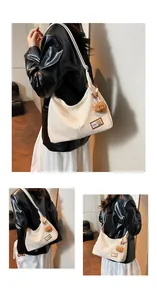 Detail of off-white hobo bag with teddy bear charm and fashion label on synthetic leather