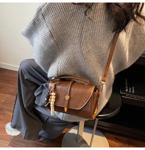 Detail view of a vintage brown leather Boston bag with wooden bead charm and metal buckle