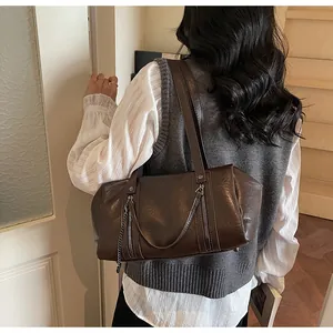 Detail of dark brown leather Boston bag with vertical zippers and metallic chain accent