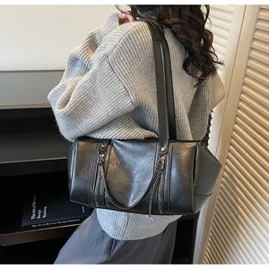 Side view of black Boston bag with dual vertical zippers and silver chain details