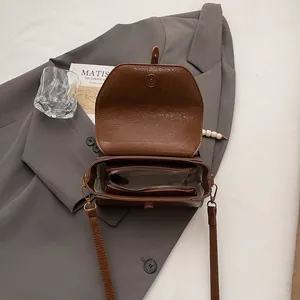 Brown retro Boston small square bag with leather texture on a grey suit background