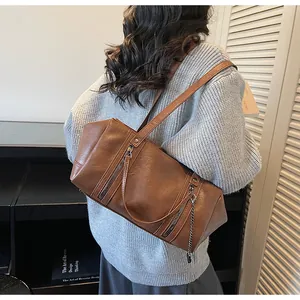 Rear view of a retro brown leather Boston bag with metal zippers and chain decoration