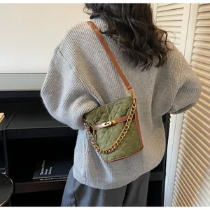 Quilted green bucket bag with brown leather trim and gold chain detail on model