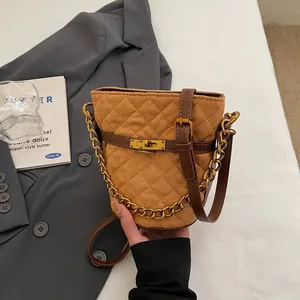 Quilted camel bucket bag with metallic chain and gold turn-lock closure in lifestyle setting