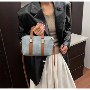 Detail of blue tote bag with brown leather handles and adjustable shoulder strap