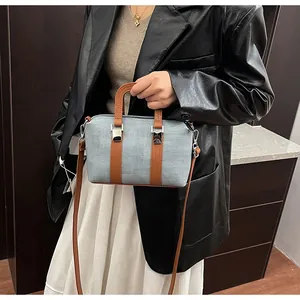 Detail of Boston-style blue textured bag with brown leather straps and metal hardware