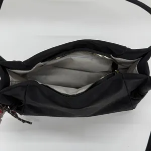 Vue intérieure du sac bandoulière noir montrant le compartiment principal et la poche zippée