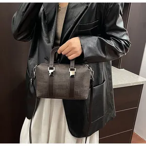 Detail of a dark brown woven Boston bag featuring silver metal buckles and top handles