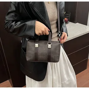 Macro detail of dark brown Boston bag with textured finish and silver metal buckle