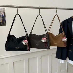 Trois sacs d'épaule minimalistes en similicuir noir, marron foncé et caramel avec pendentifs