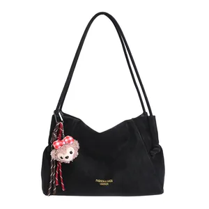 Sac fourre-tout noir en daim avec bandoulières et charm ourson sur fond blanc immaculé