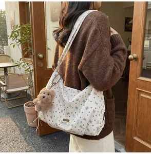 Detailansicht der cremeweißen Cord-Tasche mit Bärenmuster und Plüsch-Anhänger